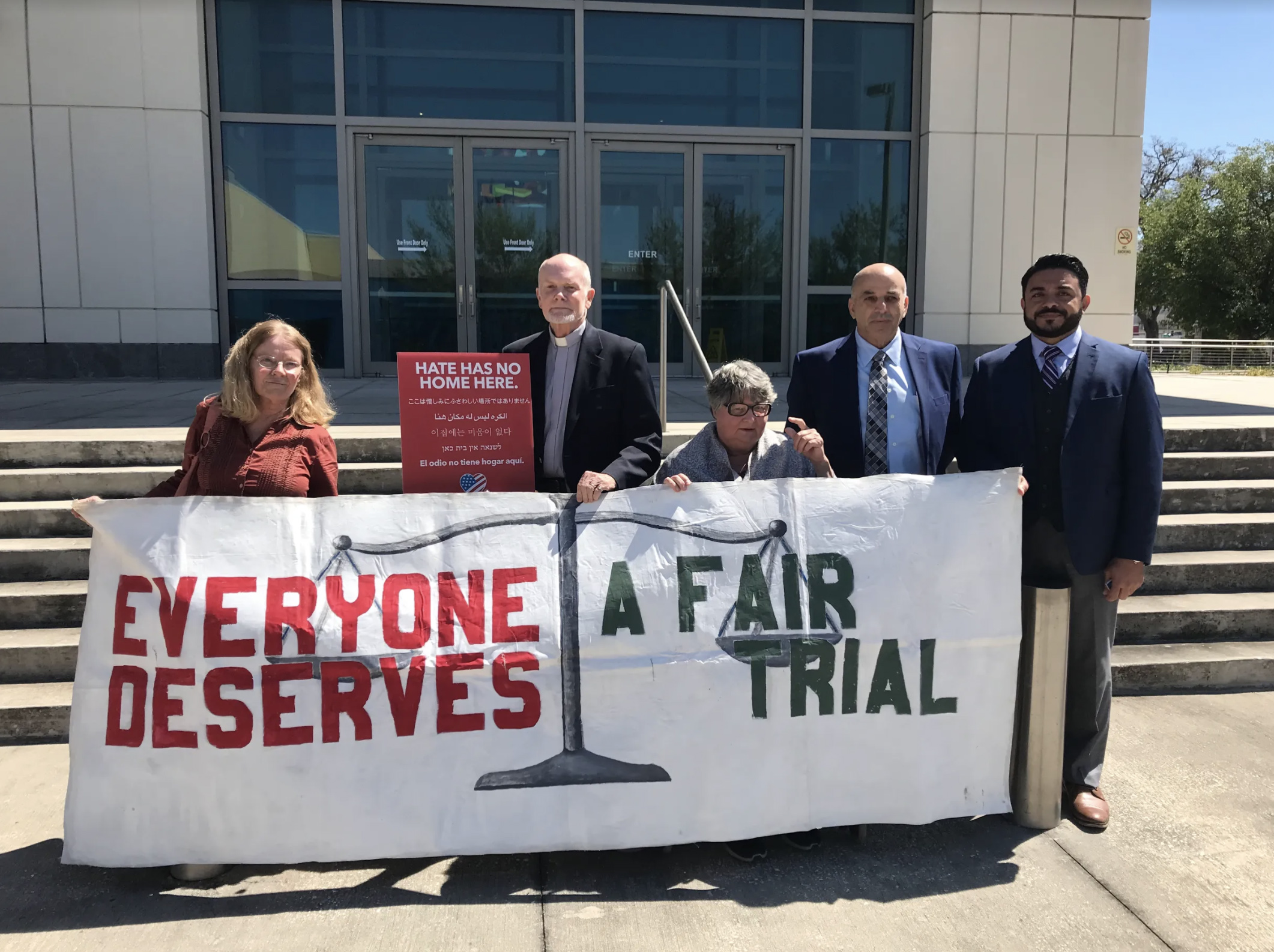 group of people holding banner front of building